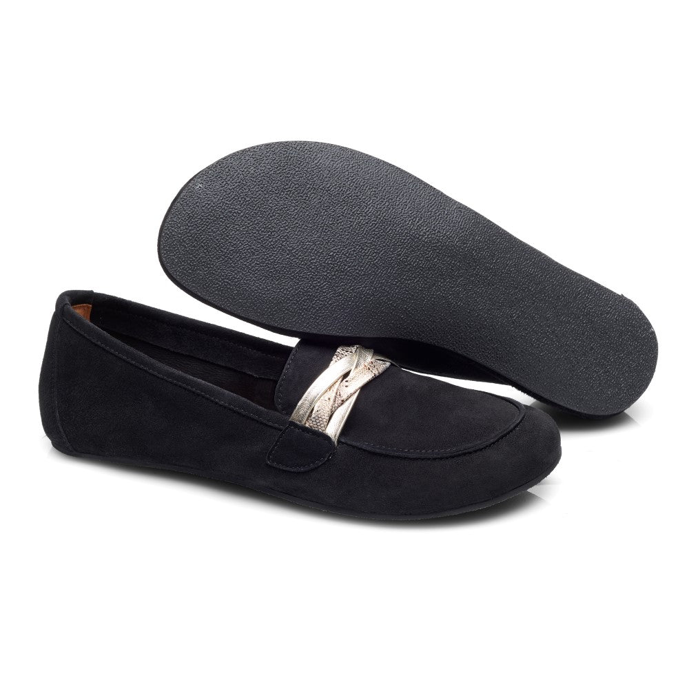 Der QERP Velours Black von ZAQQ ist ein Paar eleganter schwarzer Mokassins, die oben mit einem dekorativen Metallband verziert sind. Ein Schuh steht aufrecht, während der andere auf der Seite liegt und seine strukturierte Sohle zeigt.