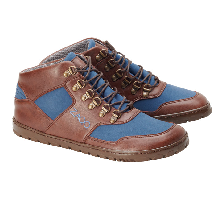 Wir präsentieren die wasserdichten High-Top-Sneaker HIQE Mid Vegan Blue von ZAQQ, die sich durch ihre robuste Sohle auszeichnen und als vegane Wanderschuhe gefertigt sind. Mit braunen Lederakzenten, blauen Stoffeinsätzen, Metallösen und Schnürsenkeln mit dem ZAQQ-Logo an der Seite verbinden diese Sneaker auf kunstvolle Weise Stil mit Umweltbewusstsein.