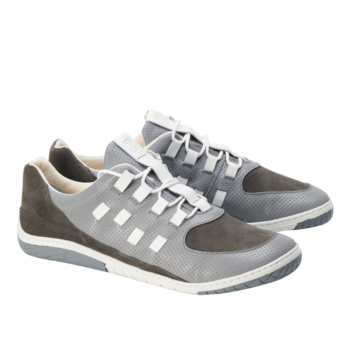 Die BRISQ Grey Sneaker von ZAQQ präsentieren ein stilvolles Barfußschuh-Design mit weißen Akzenten und einem einzigartigen Schnürmuster. Diese Schuhe sind aus Nappaleder mit perforierter Textur gefertigt und haben mit ihren weißen Sohlen, die durch graue Details akzentuiert werden, einen modernen, sportlichen Look.