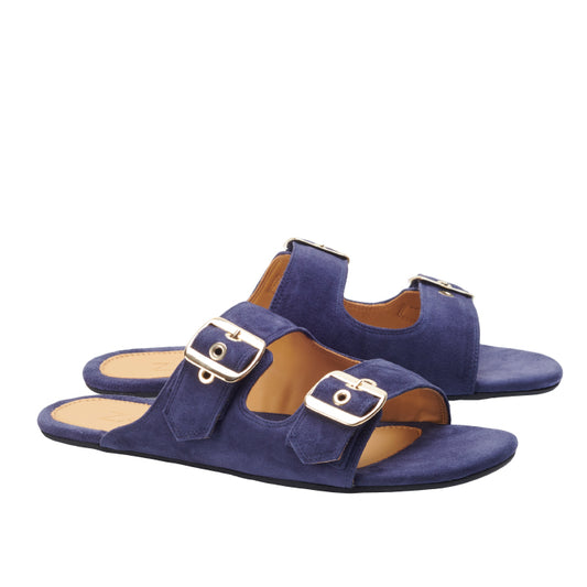 Ein Paar UQO Blue-Sandalen von ZAQQ mit offenen Zehen und goldenen Schnallenriemen vor weißem Hintergrund.