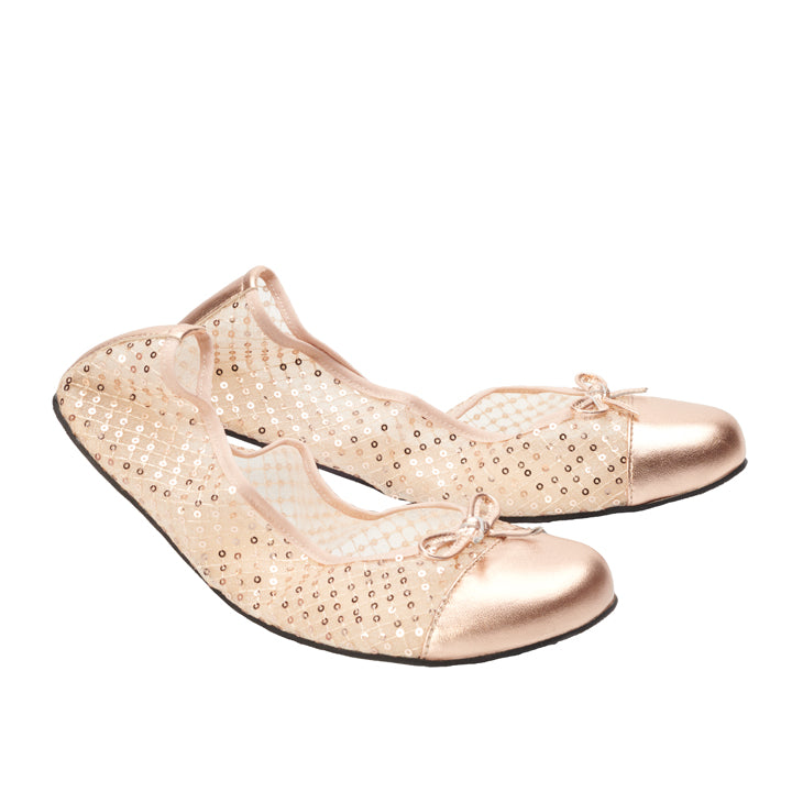 Wir präsentieren die TWIST SHEER Gold von ZAQQ: ein Paar elegante Ballerinas aus goldenem Nappaleder in einem hellrosa Farbton, mit Paillettendetails und glänzenden Zehenkappen. Jeder Schuh ist für ultimativen Komfort konzipiert und verfügt über eine kleine dekorative Schleife an der Oberseite. Vor einem schlichten weißen Hintergrund verströmen diese Schuhe einen Hauch von raffiniertem Charme.