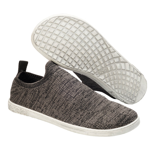 Ein Paar ZAQQ SQIN Grey Slip-On-Sneaker in stilvollem Grau mit gestrickter Textilgewebe-Textur. Sie verfügen über weiße, strukturierte Gummisohlen, die von der Seite und von unten gezeigt werden, und haben eine schwarze Aufreißlasche an der Ferse – ein wahres Vergnügen.