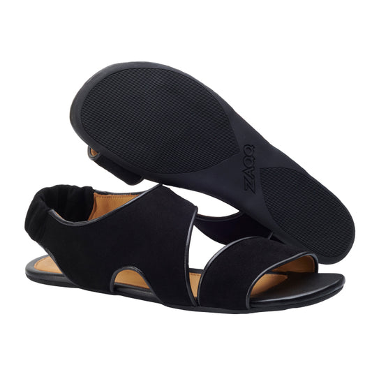 Ein Paar CISQA Black Sandalen mit offener Spitze von ZAQQ mit elastischen Riemen an der Rückseite wird präsentiert, wobei ein Schuh aufrecht steht, während der andere seine Gummisohle zeigt. Diese Sandalen bieten einen schlichten, modernen Look mit minimalistischem Design, ergänzt durch innovative Barfußtechnologie für maximalen Komfort.