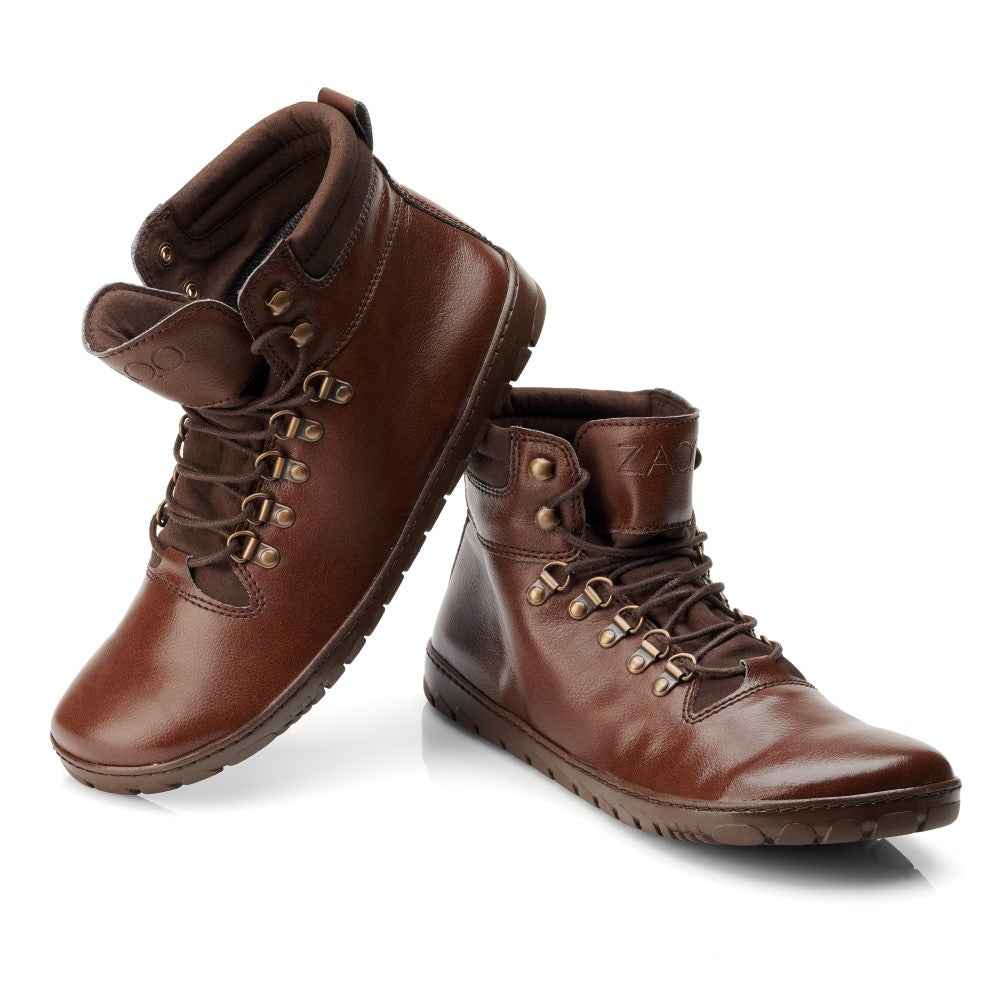 Ausgestellt wird ein Paar EXPEQ Vegan Marone Waterproof Outdoor-Stiefel von ZAQQ. Diese Stiefel haben einen hohen Schaft und einen gepolsterten Schaft, mit braunen Schnürsenkeln, die durch Metallösen geführt sind. Ihre flachen, gemusterten Sohlen bieten hervorragenden Halt. Sie sind leicht erhöht positioniert und bieten sowohl eine Seiten- als auch eine Vorderansicht, perfekt für jedes Abenteuer.