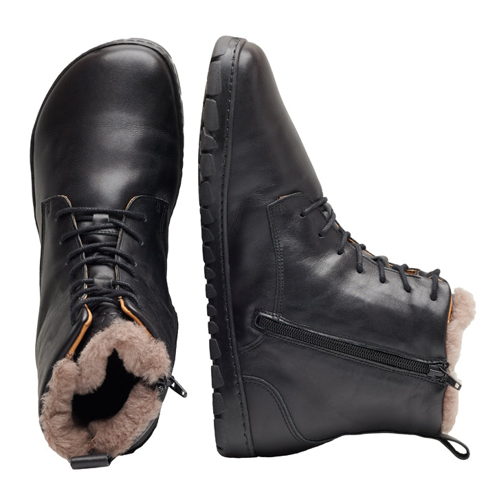 Ein Paar QUINTIC Winter Black-Stiefel von ZAQQ. Ein Stiefel ist von oben zu sehen und zeigt ein flauschiges, braunes, mit Lammfell gefüttertes Futter, während der andere Stiefel von der Seite zu sehen ist und einen Reißverschluss und eine robuste Sohle aufweist.