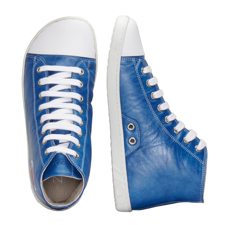 Wir präsentieren den CHUQQS Blue von ZAQQ: Ein stylisches Paar blauer High-Top-Sneaker aus hochwertigem Nappaleder, mit weißen Schnürsenkeln und der charakteristischen ZAQQ SNEAKER Sohle. Ein Sneaker wird von der Seite präsentiert, während der andere von oben gezeigt wird, was sein einzigartiges Design und die aufwendigen Nähte betont.