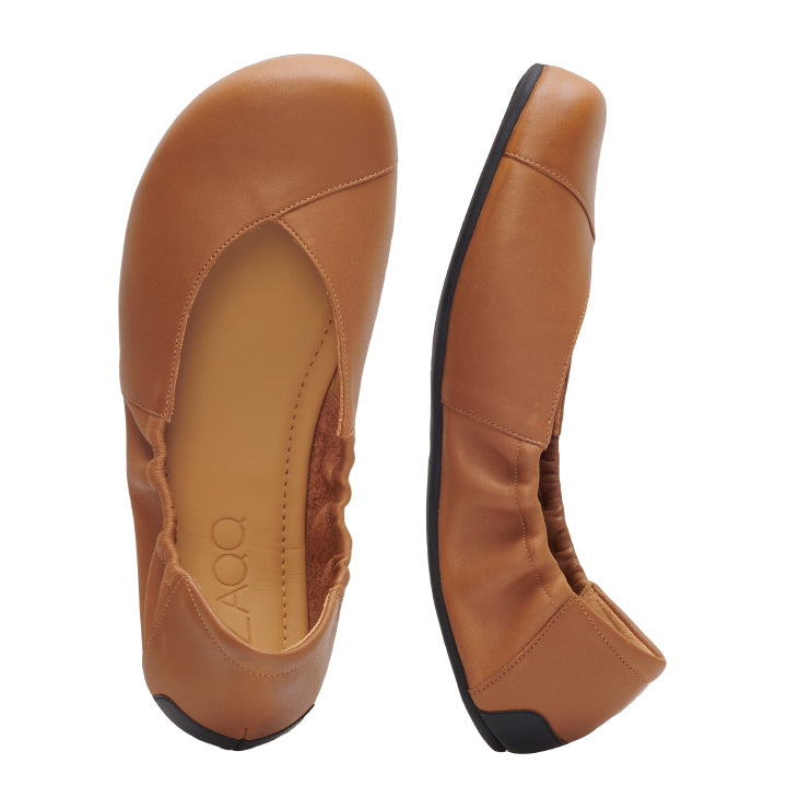 Ein Paar braune ZAQQ MAIQA Ballerinas mit Gummizug, von oben und von der Seite. Die Schuhe bestehen aus einem glatten, lederähnlichen Material mit schwarzen Sohlen und einer flexiblen Sohle, ergänzt durch ein bequemes, abgerundetes Zehendesign.