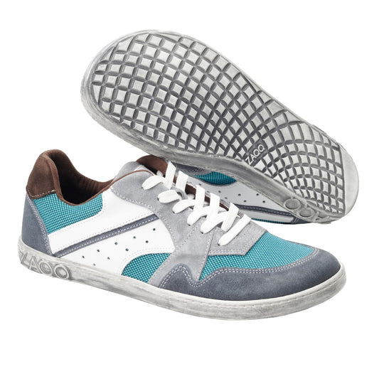 Wir präsentieren den BREAQ Turquoise von ZAQQ, ein Paar stylische Sneaker mit blaugrünen, weißen und grauen Einsätzen, ergänzt durch weiße Schnürsenkel und braune Akzente. Diese Schuhe wurden mit Blick auf außergewöhnlichen Komfort entworfen und bieten bei jedem Schritt sowohl Flair als auch Funktionalität.