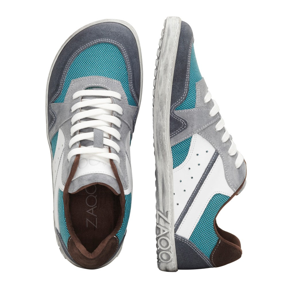 Wir präsentieren den BREAQ Turquoise von ZAQQ, ein Paar stylische Sneaker mit blaugrünen, weißen und grauen Einsätzen, ergänzt durch weiße Schnürsenkel und braune Akzente. Diese Schuhe wurden mit Blick auf außergewöhnlichen Komfort entworfen und bieten bei jedem Schritt sowohl Flair als auch Funktionalität.