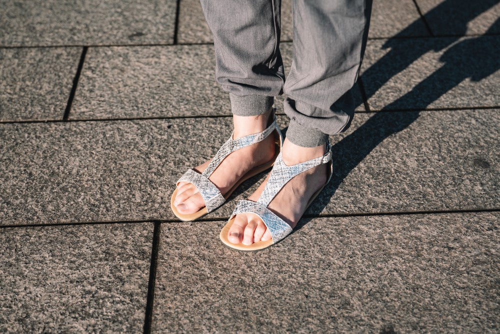 CLIQ Silver-Sandalen von ZAQQ mit silbernem Metallic-Finish, offenen Zehen, Knöchelriemen und einer Kautschuksohle auf weißem Hintergrund.