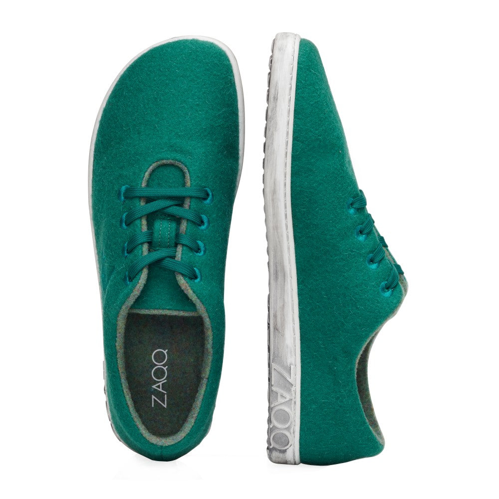 Die LIQE Green Sneaker von ZAQQ im minimalistischen Design sind in Grün mit Schnürsenkeln und weißer Sohle erhältlich. Der Markenname ist deutlich sichtbar an der Seite der Sohle zu sehen. Sowohl von oben als auch von der Seite betrachtet sind diese Schuhe für diejenigen gemacht, die Einfachheit und Komfort schätzen.