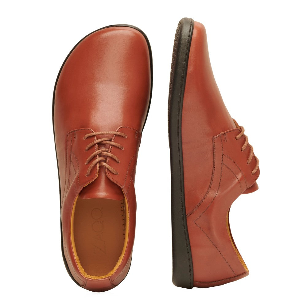 Gezeigt wird eine Draufsicht und eine Seitenansicht der Schnürschuhe PEAQ Cognac aus braunem Leder der Marke ZAQQ. Die Schuhe mit glattem Glattleder-Finish und schwarzen Sohlen stehen auf einem weißen Hintergrund.