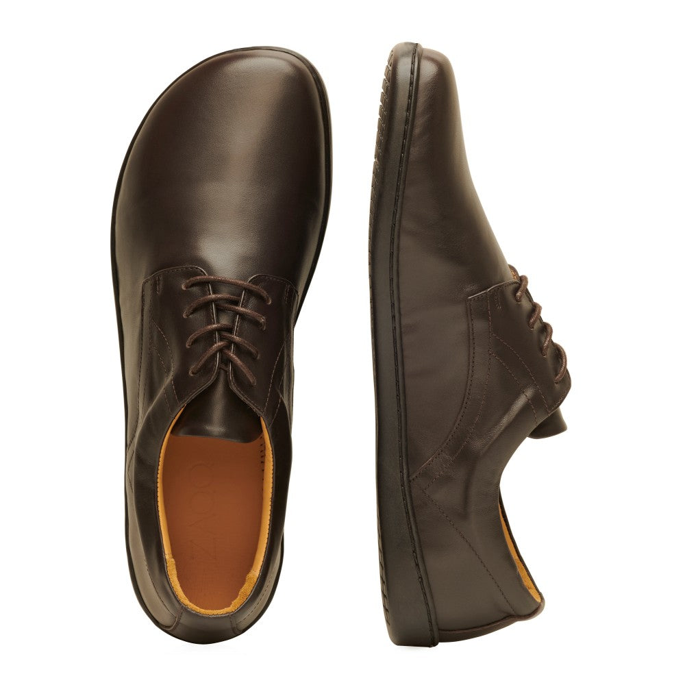 Die PEAQ Dark Brown-Schuhe von ZAQQ werden von oben und von der Seite elegant präsentiert und heben ihr minimalistisches Design und den Schnürverschluss hervor. Diese Business-Casual-Halbschuhe zeichnen sich durch ein glattes, poliertes Finish und eine dünne, flexible Sohle aus.