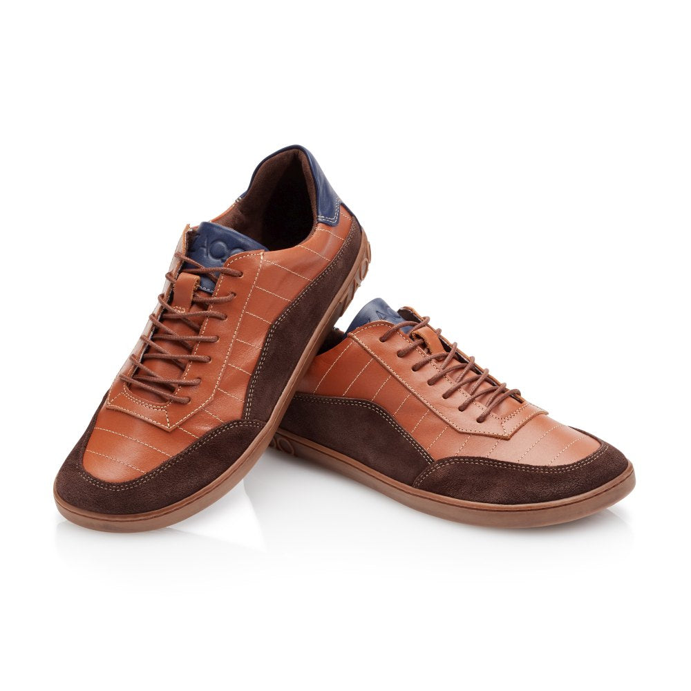 Wir präsentieren den QAMPION Brown von ZAQQ: ein anspruchsvolles Paar Sneaker aus stilvollem braunem Leder mit Wildlederakzenten und blauen Details. Ein Schuh steht aufrecht, während der andere daran lehnt und sein Design wunderschön zur Geltung bringt. Sie verfügen über eine flexible Kautschuksohle und Schnürsenkel und bieten einen lässigen Look, der durch eine kontrastierende strukturierte Sohle ergänzt wird.