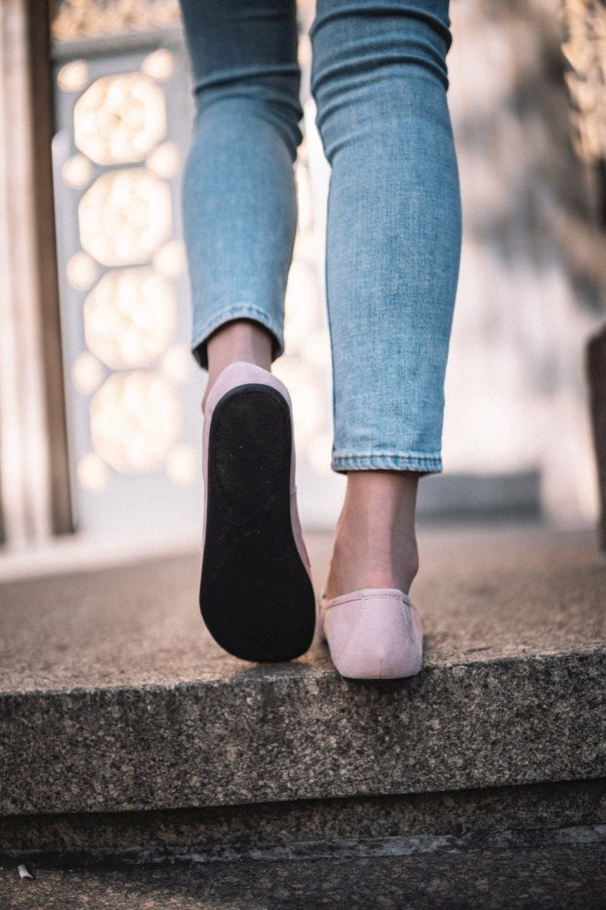 Jemand in hellblauer Jeans und QERP Candy Flats von ZAQQ mit Veloursleder-Finish steigt eine Steintreppe hinauf. Der Fokus liegt auf den Schuhen und Beinen vor einem sanft verschwommenen Hintergrund, was eine Bewegung im Freien suggeriert.