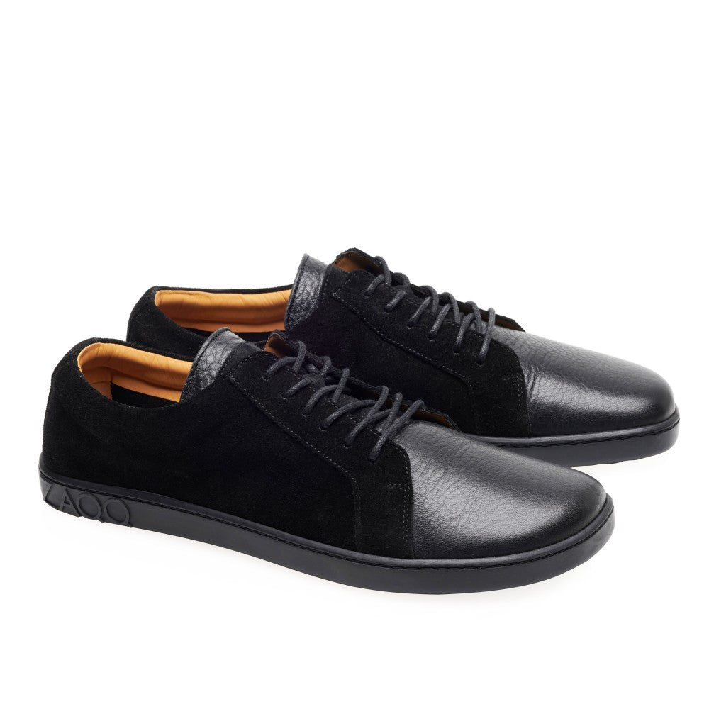 Wir präsentieren die ZAQQ QORE Low Black Sneaker, ein schickes Paar aus Glattleder und schwarzem Veloursleder. Diese schwarzen Schuhe haben passende Schnürsenkel, eine strukturierte Sohle und kontrastierende braune Innenteile – alles vor einem schlichten weißen Hintergrund.