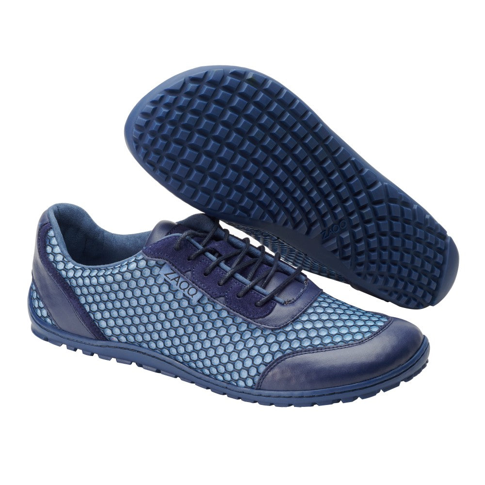 Ein Paar Sportschuhe TOQIO Navy von ZAQQ mit strukturierter Sohle und atmungsaktivem Mesh-Gewebe am Obermaterial. Ein Schuh steht aufrecht, während der andere geneigt ist, wodurch das waffelartige Sohlendesign sichtbar wird.